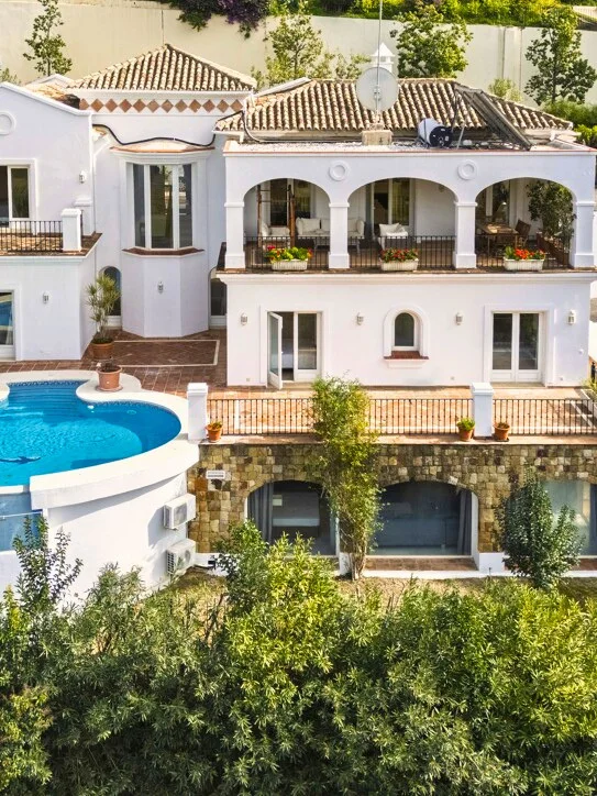 White villa with an arched loggia and a round pool