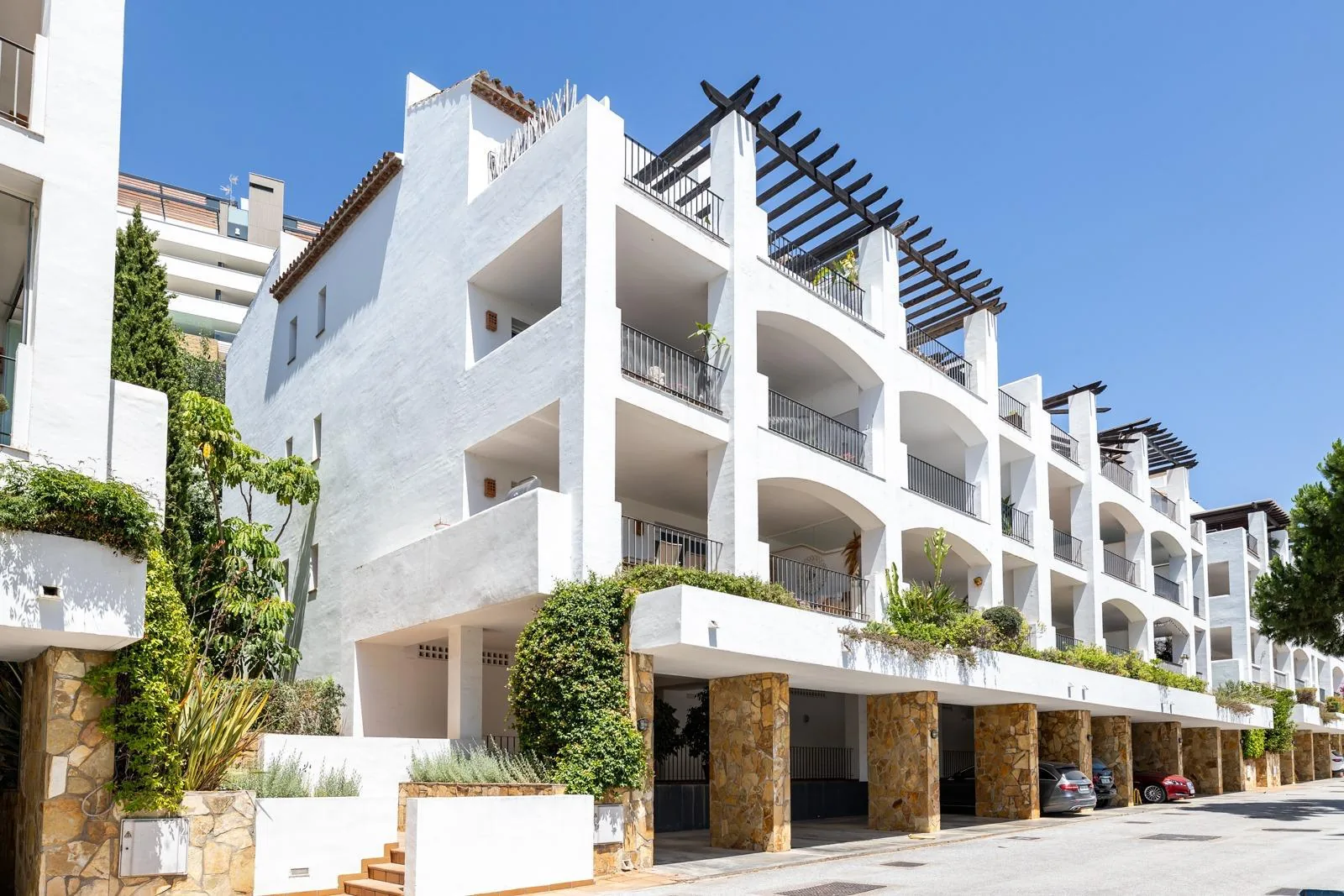 The white apartment building with its terraces and stone-clad base
