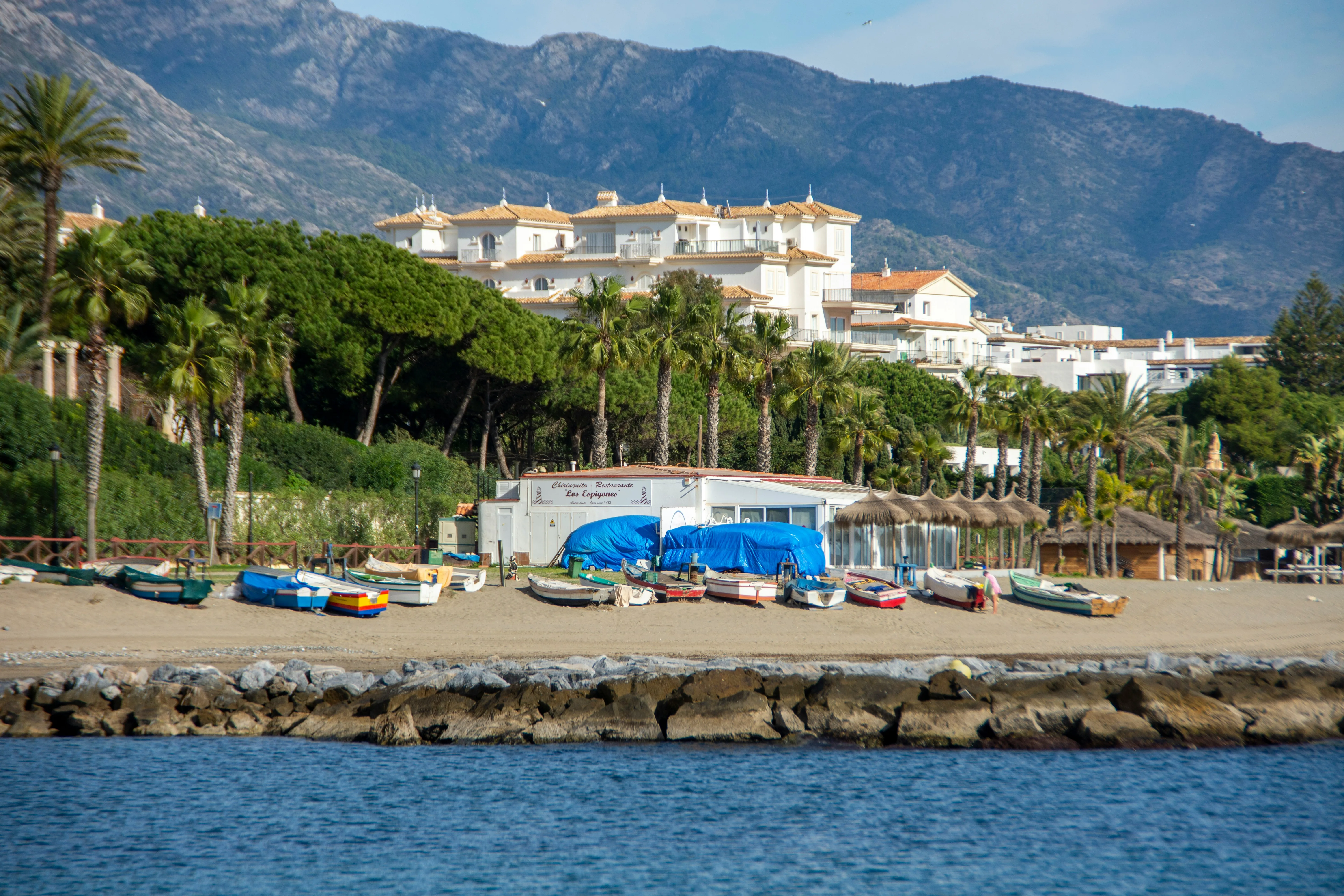 Fishing boats on the beach below white houses and the Sierra Blanca