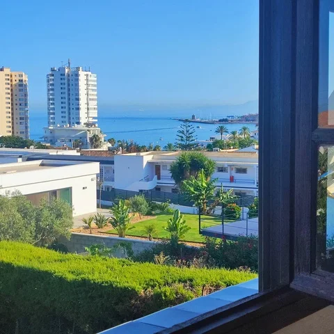 Sea view through a window frame, with tower blocks along the coast